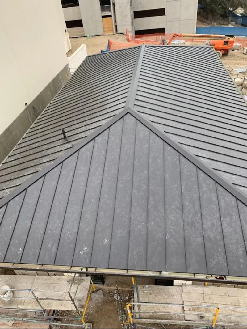 Commercial metal roof construction with crane equipment in Tarrant